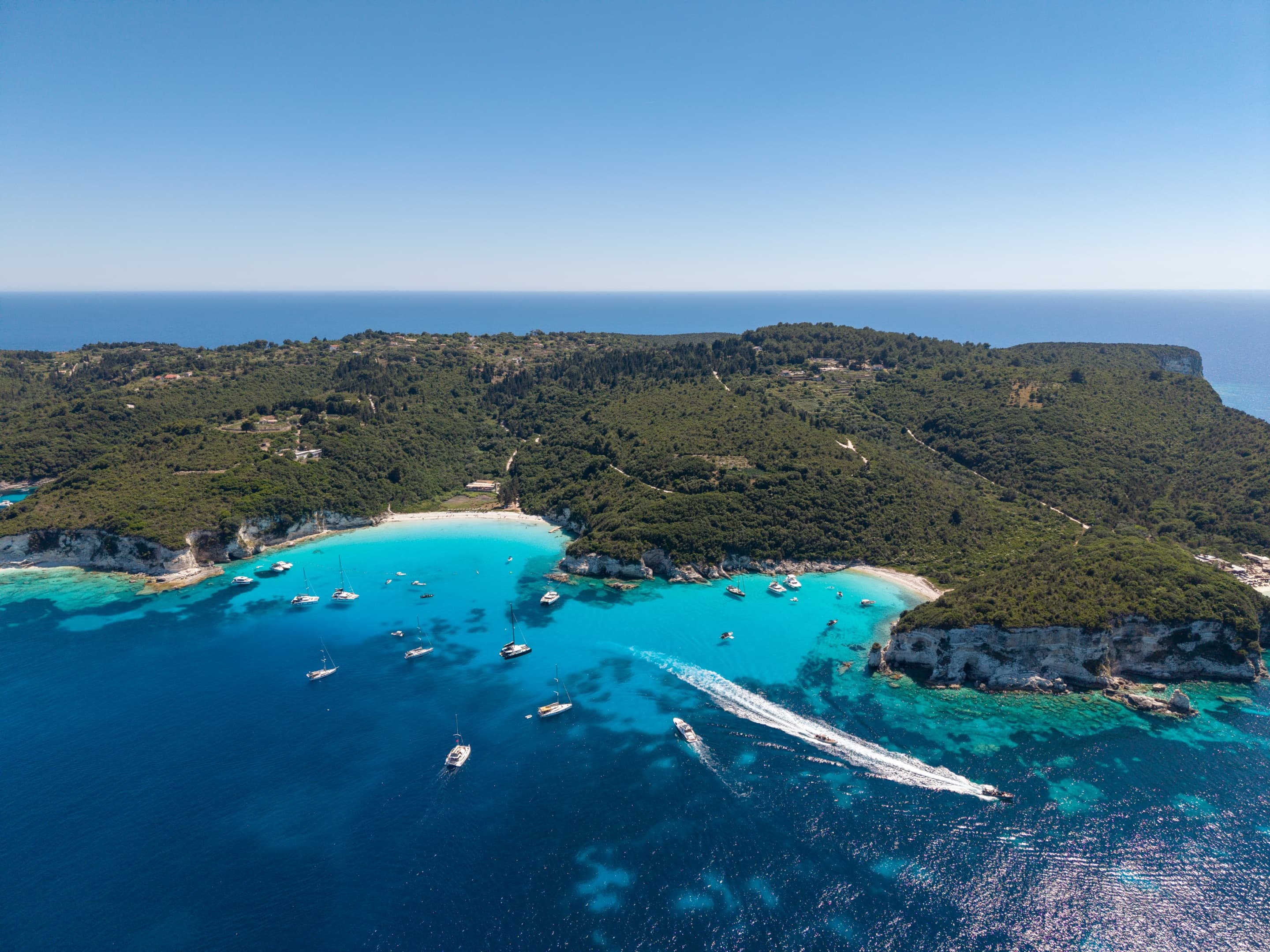 Aerial view of a turquoise Paxos bay dotted with sailboats
